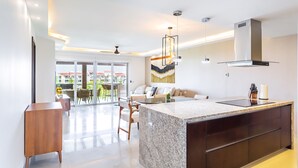 Een moderne keuken met een granieten aanrecht, donkere kastjes en een ingebouwd fornuis. Er is een eethoek met een tafel en stoelen, en een groot raam met uitzicht op het omliggende landschap.