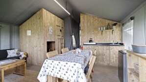 Un interior rústico de madera con una mesa de comedor para dos, una pequeña kitchenette y un rincón de estar acogedor.