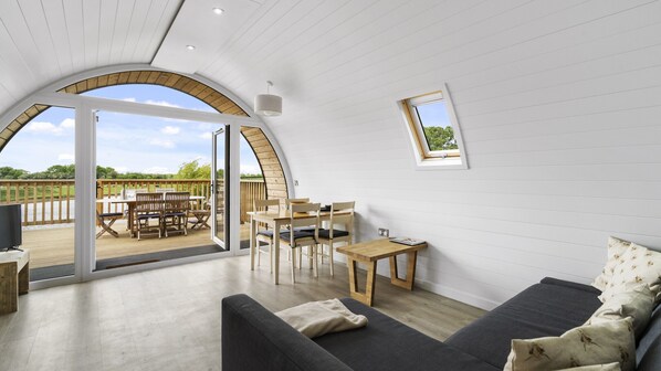 A spacious room with a large arched window, a cozy seating area with a sofa and chairs, and a small table.
