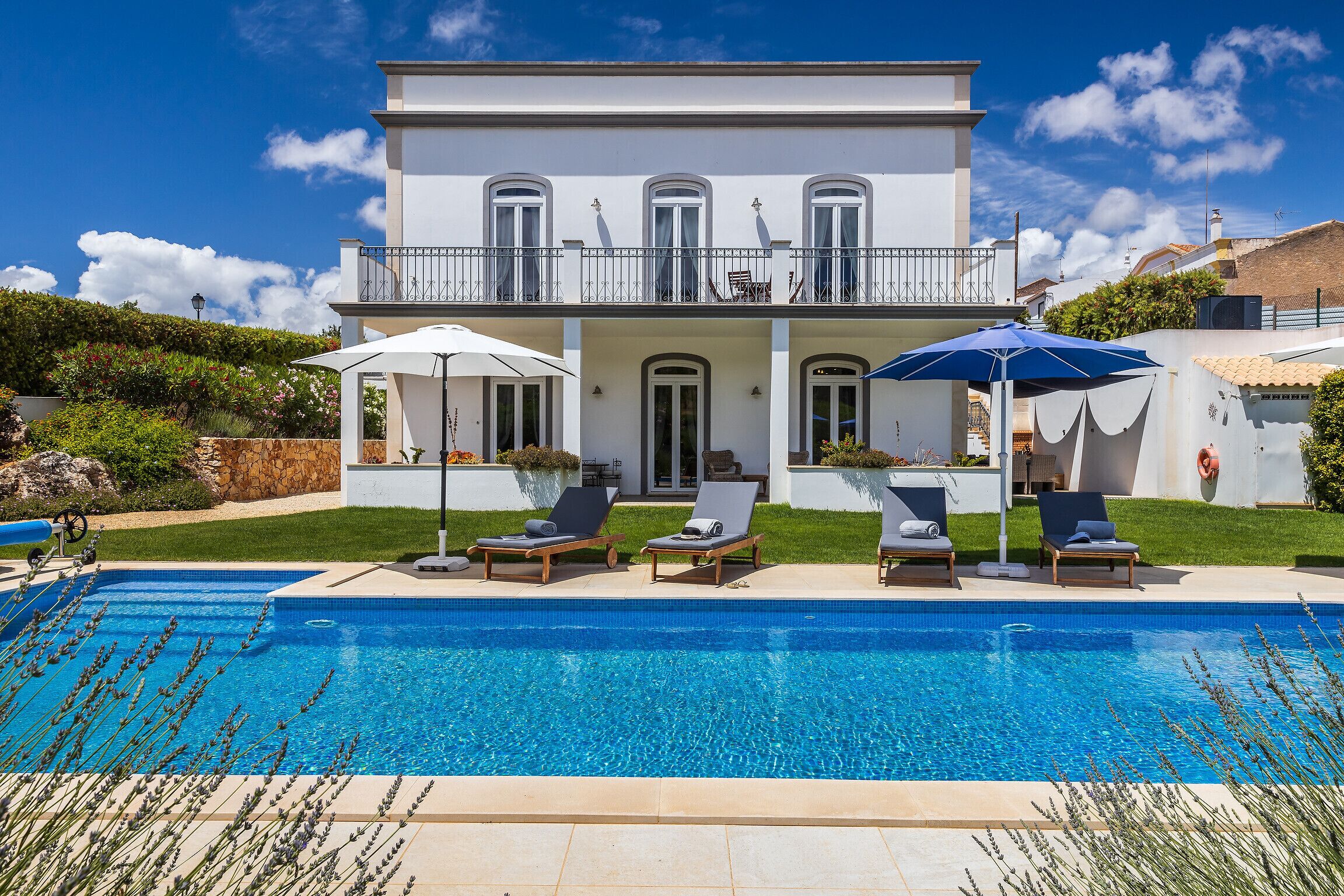 A two-story house with a swimming pool, outdoor seating, and a well-maintained garden.