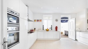 Cocina moderna con armarios blancos, dos hornos y una isla central con frutero.