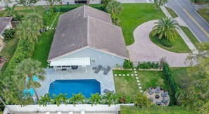 Uma casa com piscina, um pátio com cadeiras de descanso e um gramado bem cuidado.