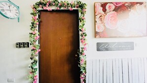 Una puerta de madera con un adorno floral, un reloj, un cartel de bienvenida y una pizarra.