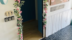 Una puerta adornada con un arco floral, un cartel de bienvenida, un reloj y una obra de arte floral enmarcada.