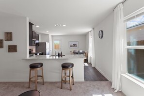 Cozinha moderna com uma ilha central, dois banquetes e uma área de jantar com mesa e cadeiras.