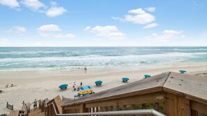 Une plage avec une terrasse en bois, des parasols et une vue sur l’océan.