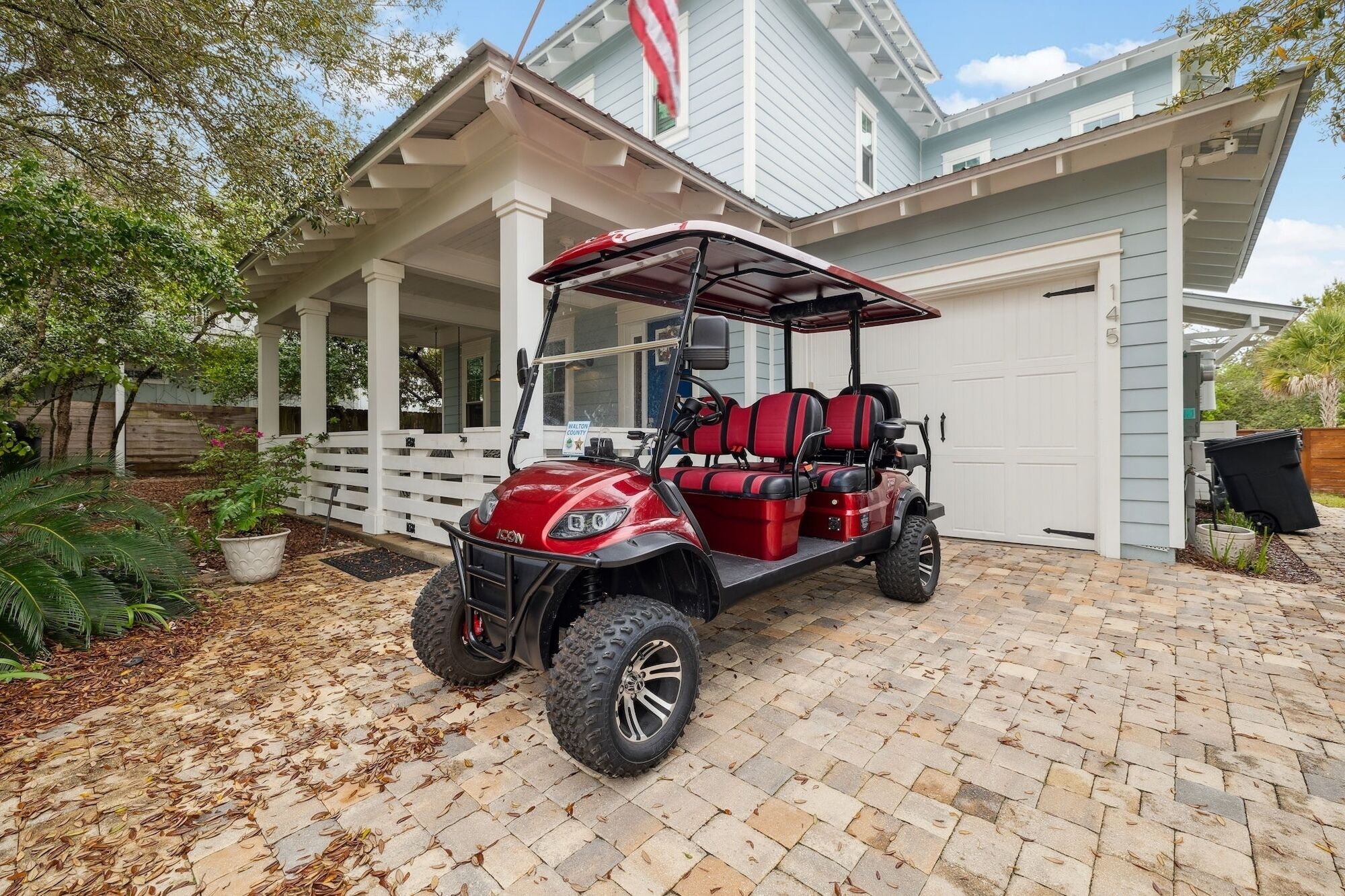 A red golf cart parked in front of a house with a porch.