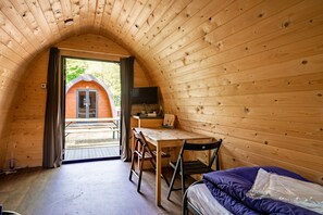 A cozy, wooden cabin with a curved ceiling, a small desk with a chair, a bed with a purple blanket, and a television on the wall. - EuroParcs Het Amsterdamse Bos (Amstelveen)