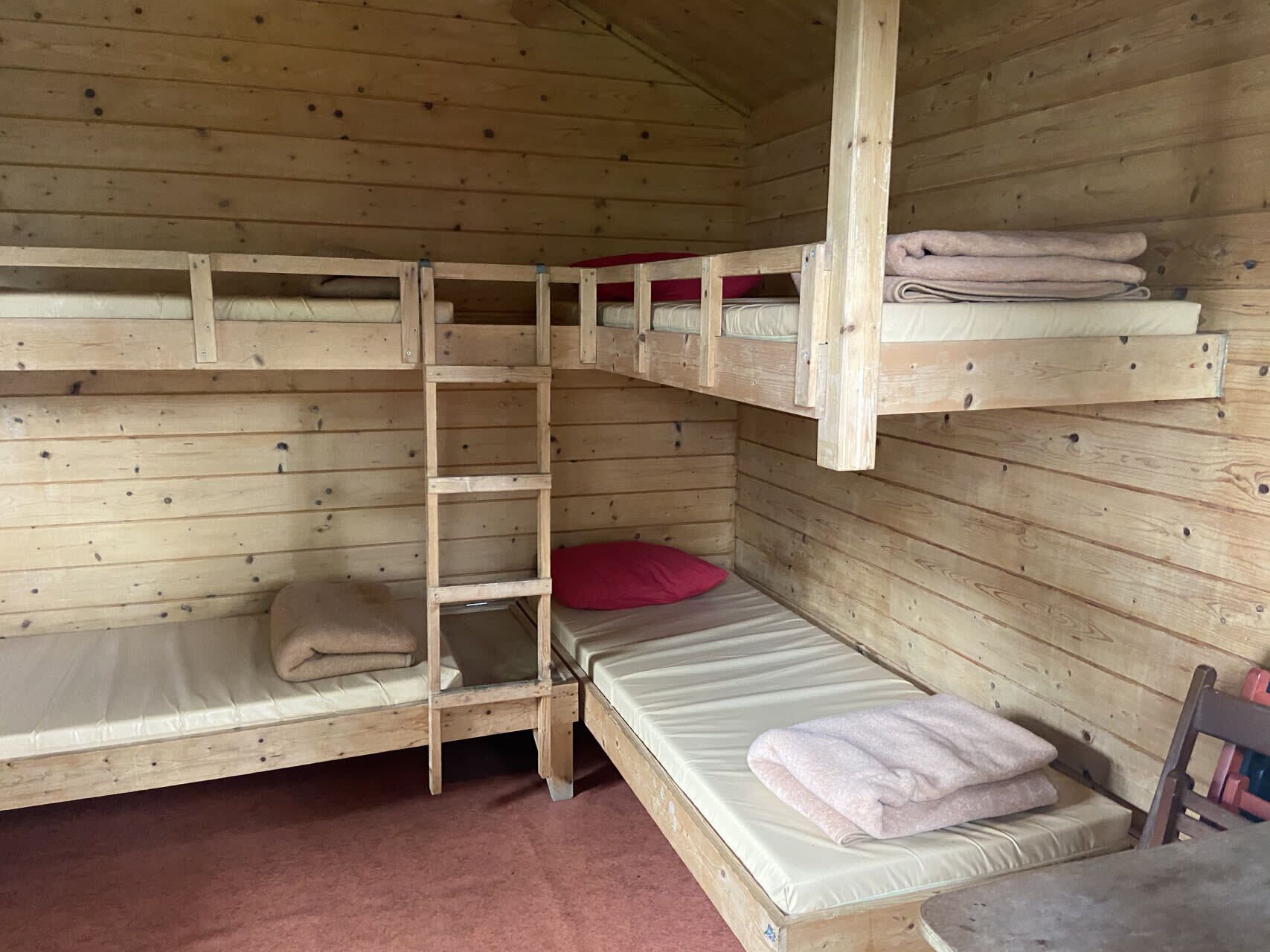 Habitación con literas, paredes de madera y una escalera.