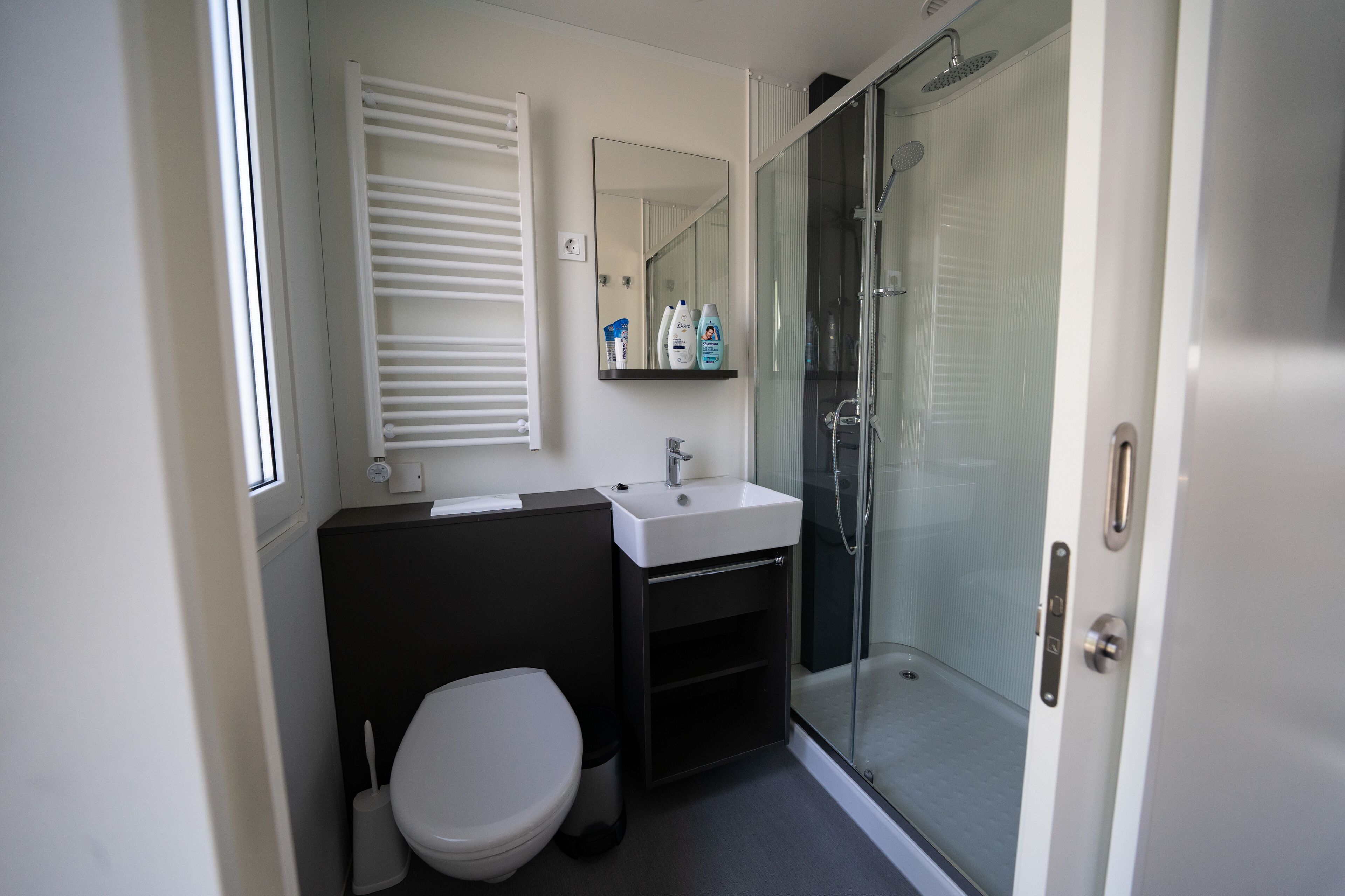 A modern bathroom with a white toilet, a black sink, and a glass shower enclosure.