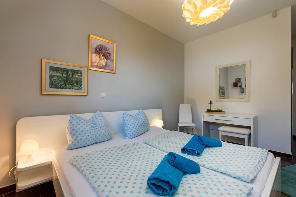 A bedroom with a bed, bedside tables, a desk, and a mirror.