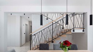 A modern interior with a wooden staircase, a dining area with a table and chairs, and a vase with flowers.