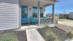 A house with a porch, a blue door, and two green Adirondack chairs. - The best vacation memories are made at the beach! Golf cart available for rent, (Port Aransas)