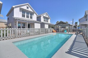 A swimming pool with a wooden deck and a white picket fence, surrounded by houses. - The best vacation memories are made at the beach! Golf cart available for rent, (Port Aransas)