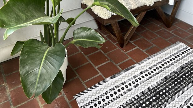 A porch with a bench, a welcome pillow, and a macrame wall hanging. - Family-Friendly 2BR Bungalow | Falcons • Concerts • Pool Access | Botel (Atlanta)