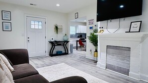 A modern living room with a sofa, a fireplace, and a flat-screen TV. - Family-Friendly 2BR Bungalow | Falcons • Concerts • Pool Access | Botel (Atlanta)