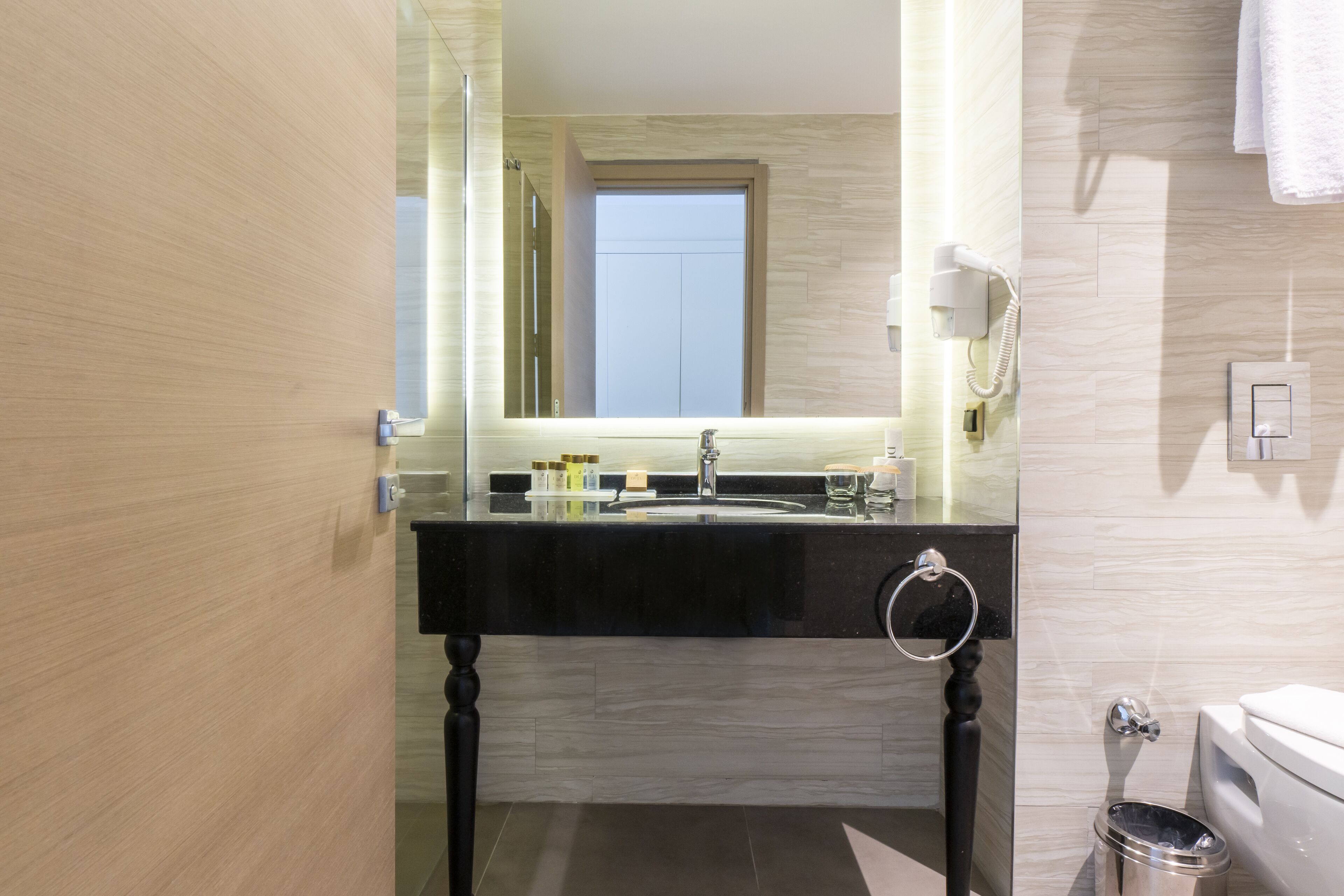 Un baño moderno con tocador negro, cabina de ducha de vidrio y retrete.