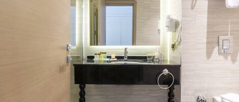 Un baño moderno con tocador negro, cabina de ducha de vidrio y retrete.
