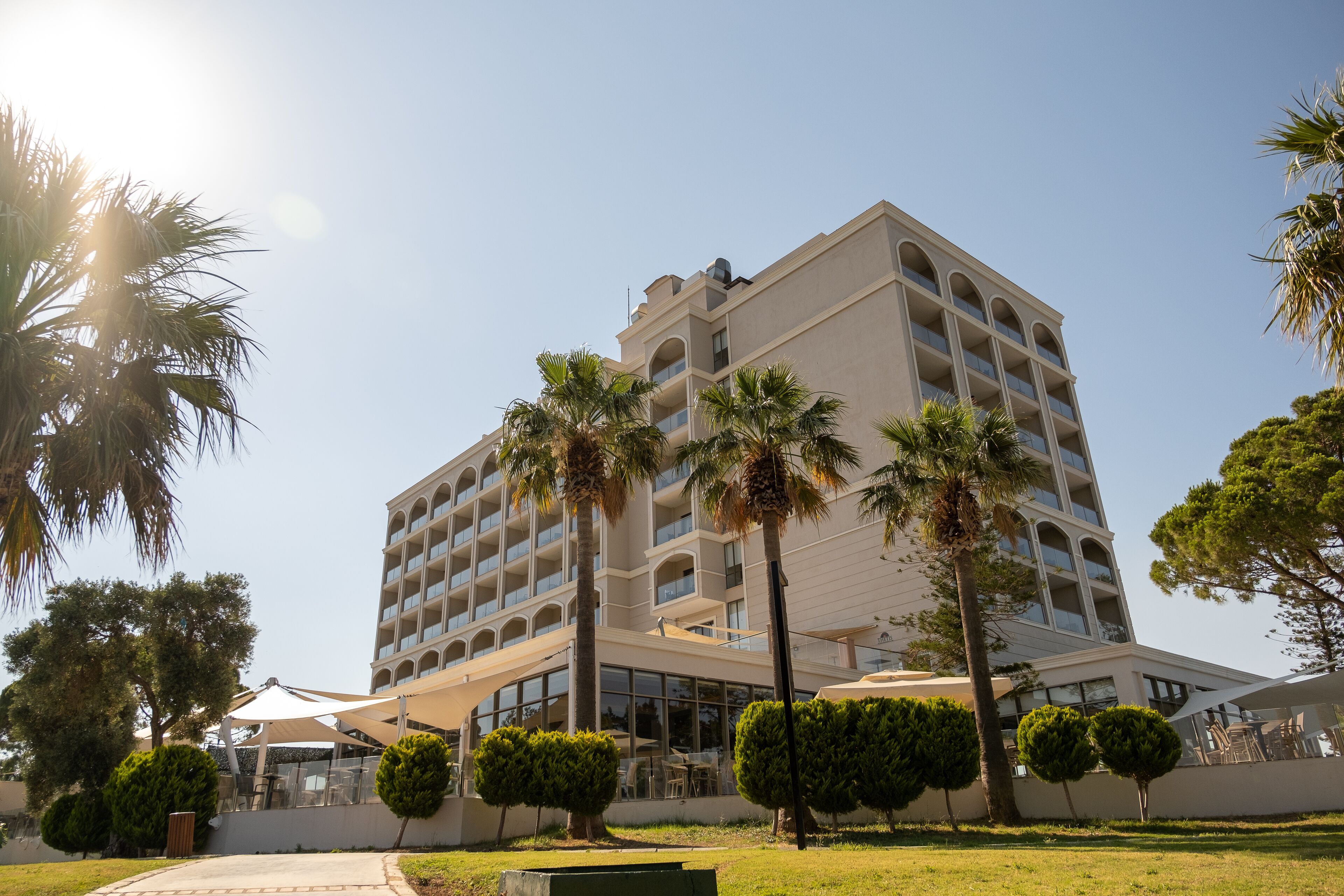 A multi-story hotel with a central courtyard, palm trees, and outdoor seating areas.