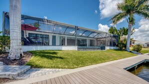 Uma casa moderna com uma estufa de vidro, um deck de madeira e um pequeno lago.