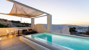Un espace piscine sur le toit avec vue sur la ville, un coin salon couvert et une table avec des chaises.