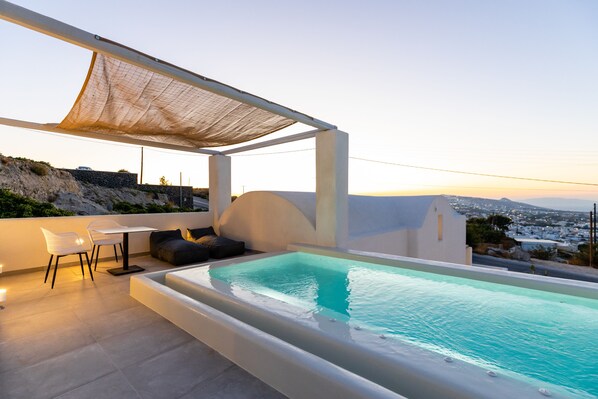 Un área de piscina en la azotea con vistas a la ciudad, una zona de estar cubierta y una mesa con sillas.