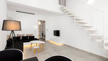 A modern interior with a staircase, a black sofa, a round table, and a floor lamp.