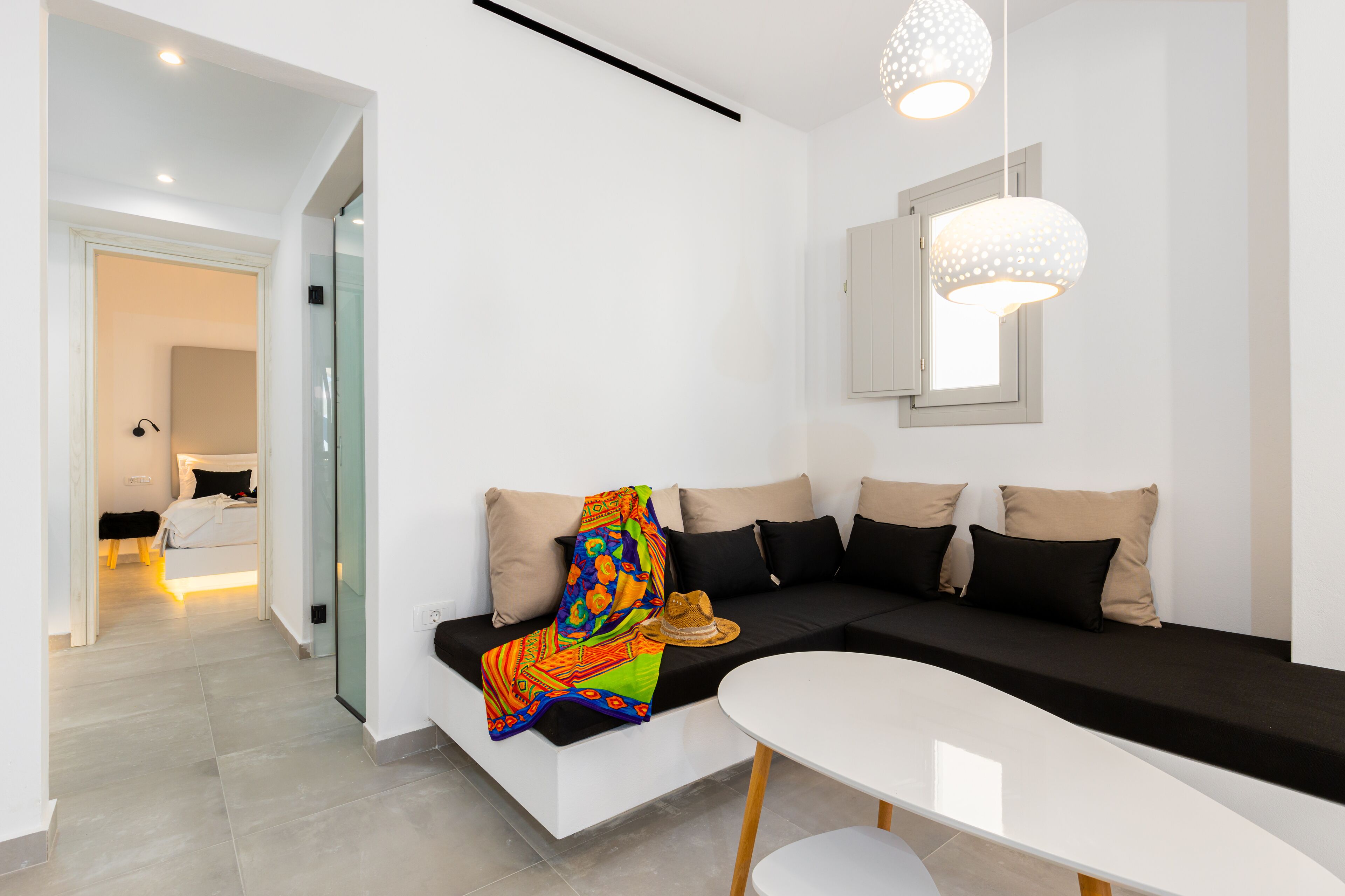 A modern living room with a black sofa, a white coffee table, and a colorful throw blanket.