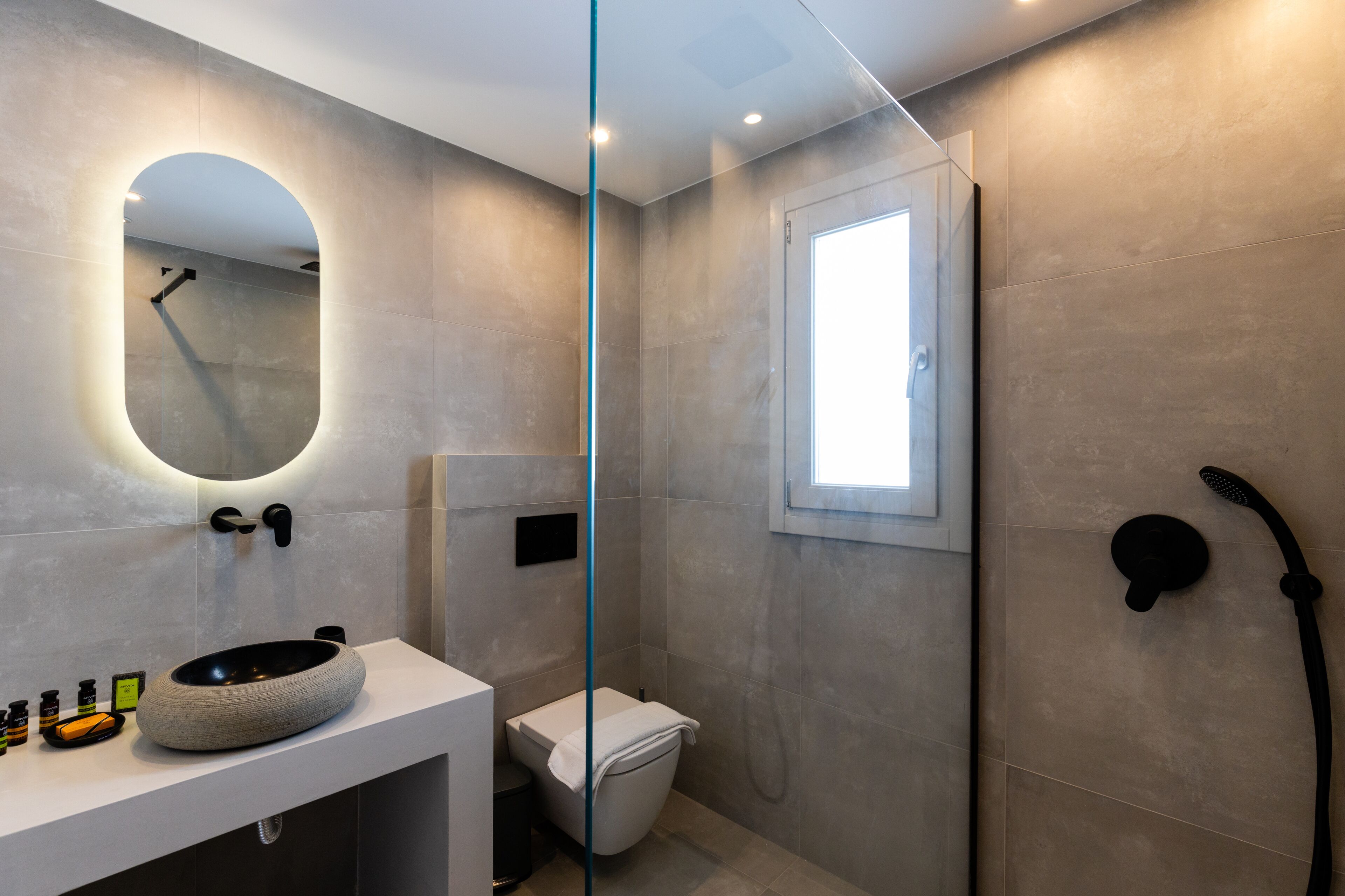 Un bagno moderno con un lavandino rotondo, un water e uno spazio doccia.