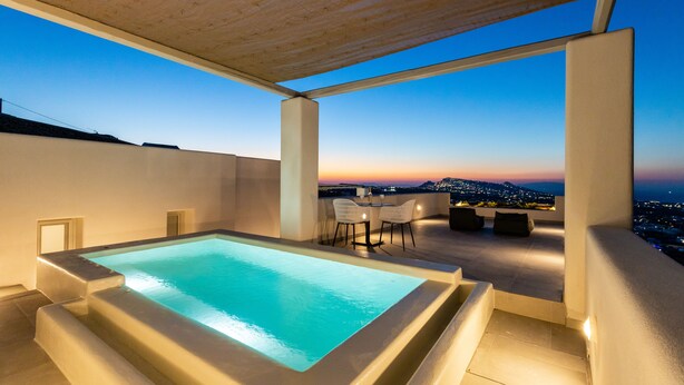 A rooftop pool with a clear view of the city at sunset. - SERAPIAS SUITES (Santorini)