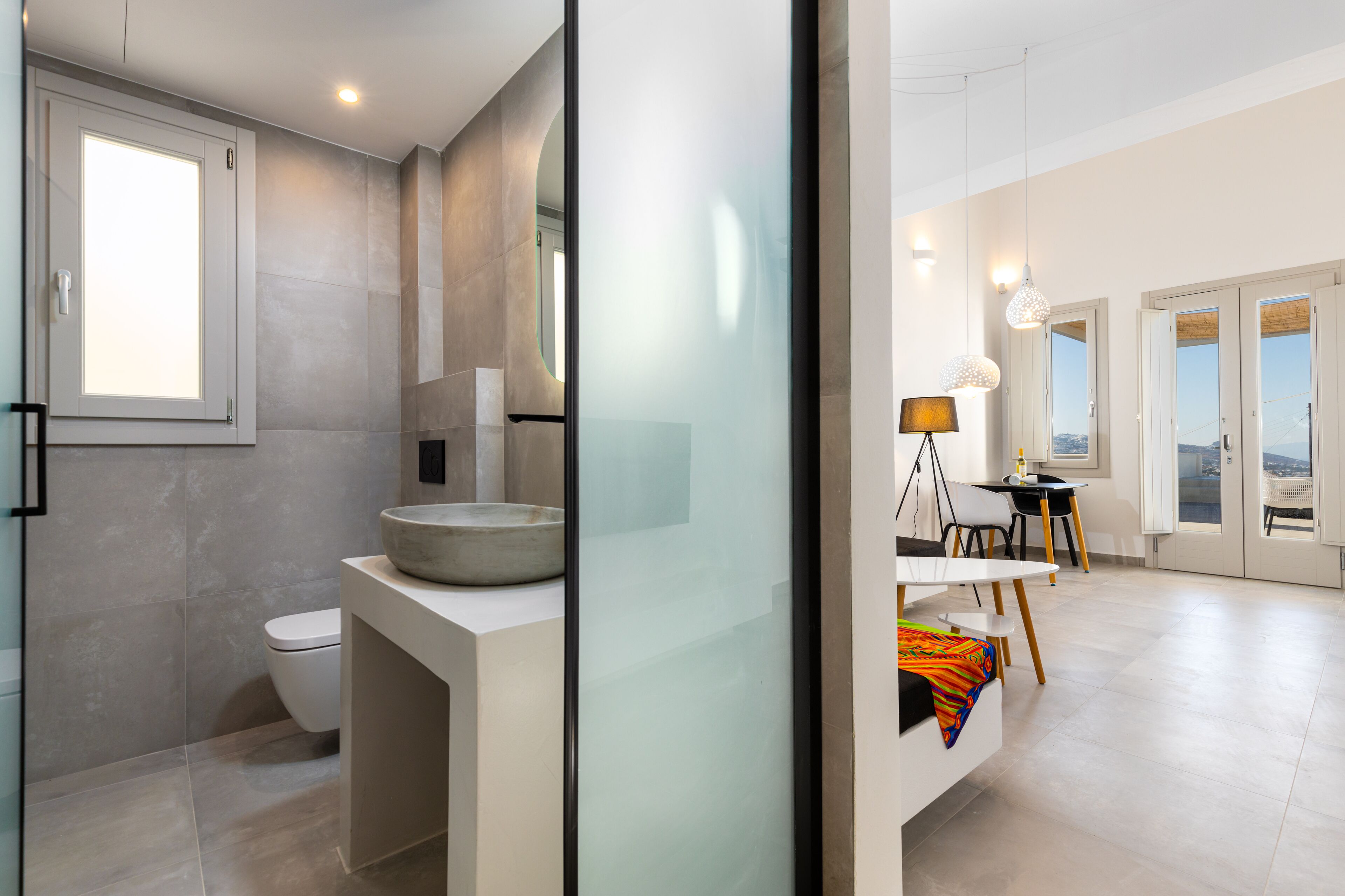 A modern bathroom with a toilet, a large mirror, and a round sink.