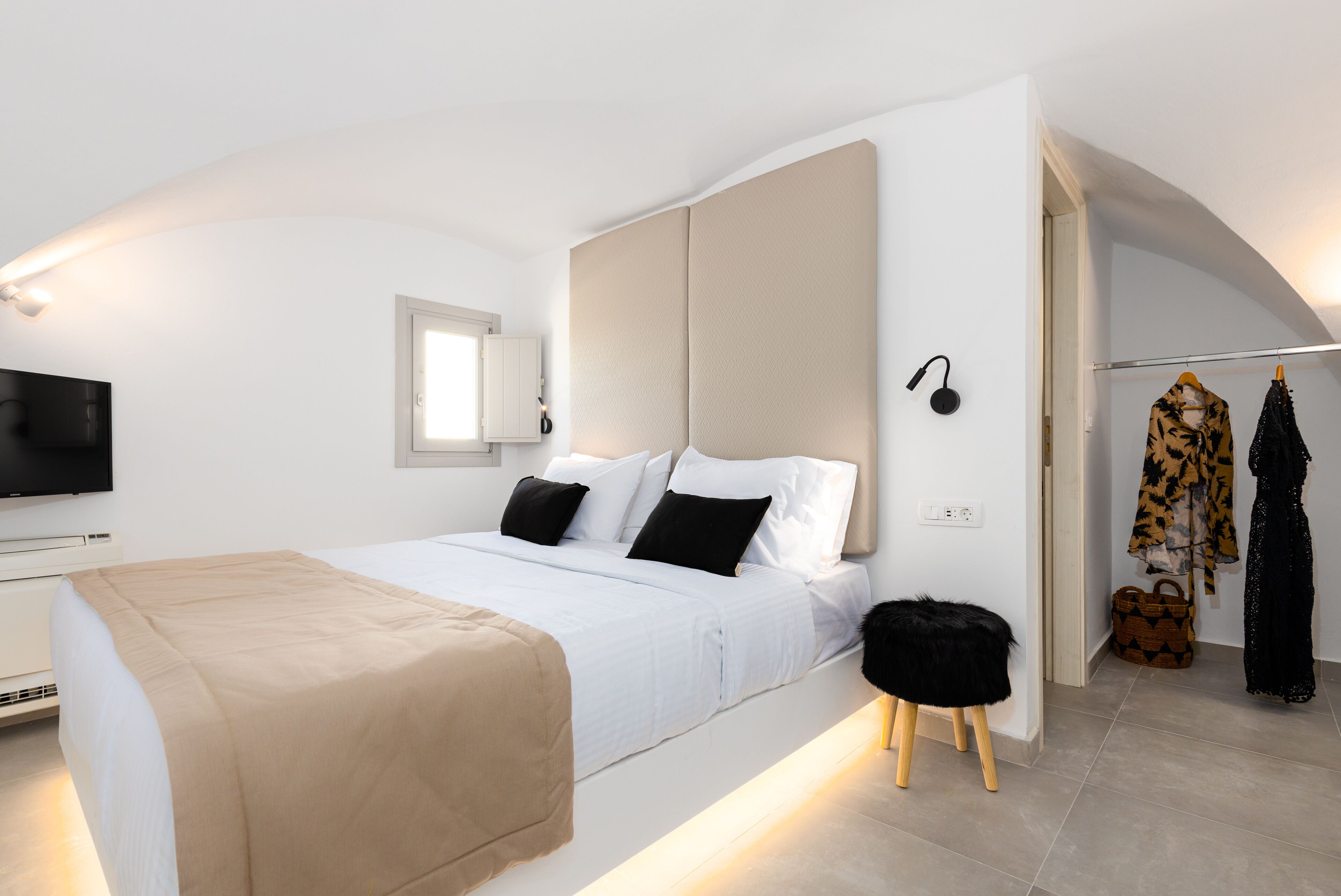 A modern bedroom with a bed, bedside table, and a television.
