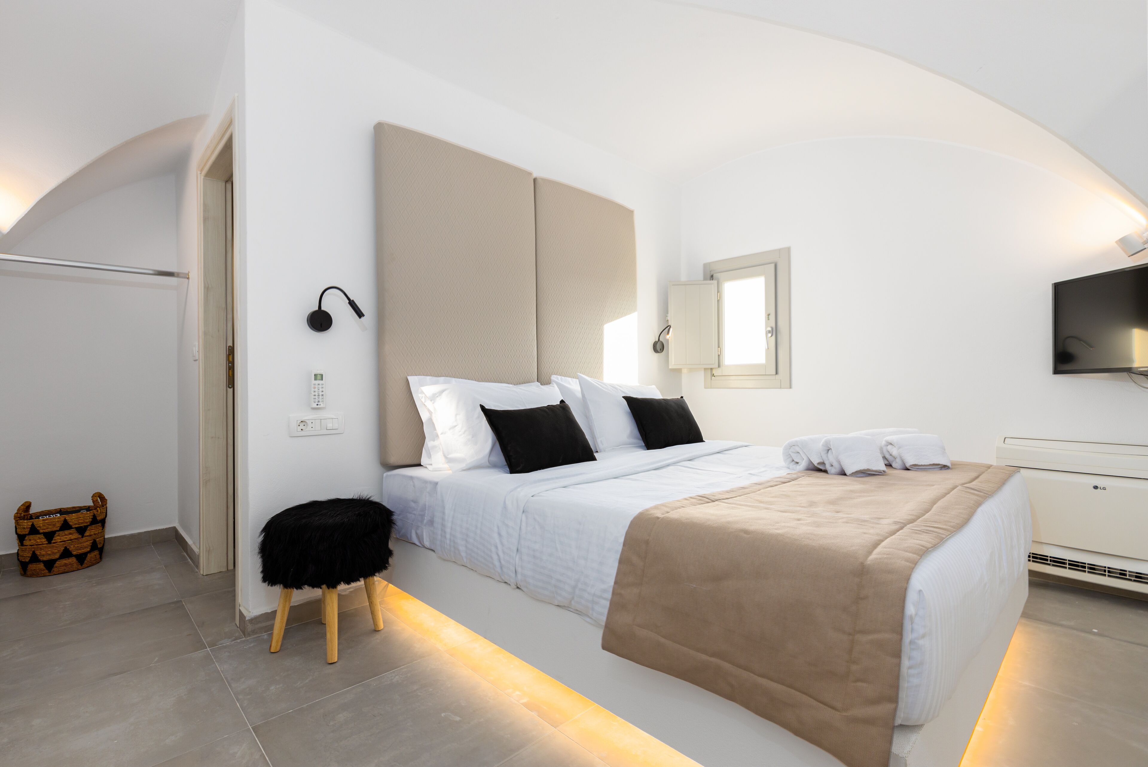 A modern hotel room with a large bed, a bedside table, a chair, a TV, and a window.