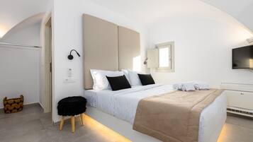 A modern hotel room with a large bed, a bedside table, a chair, a TV, and a window.