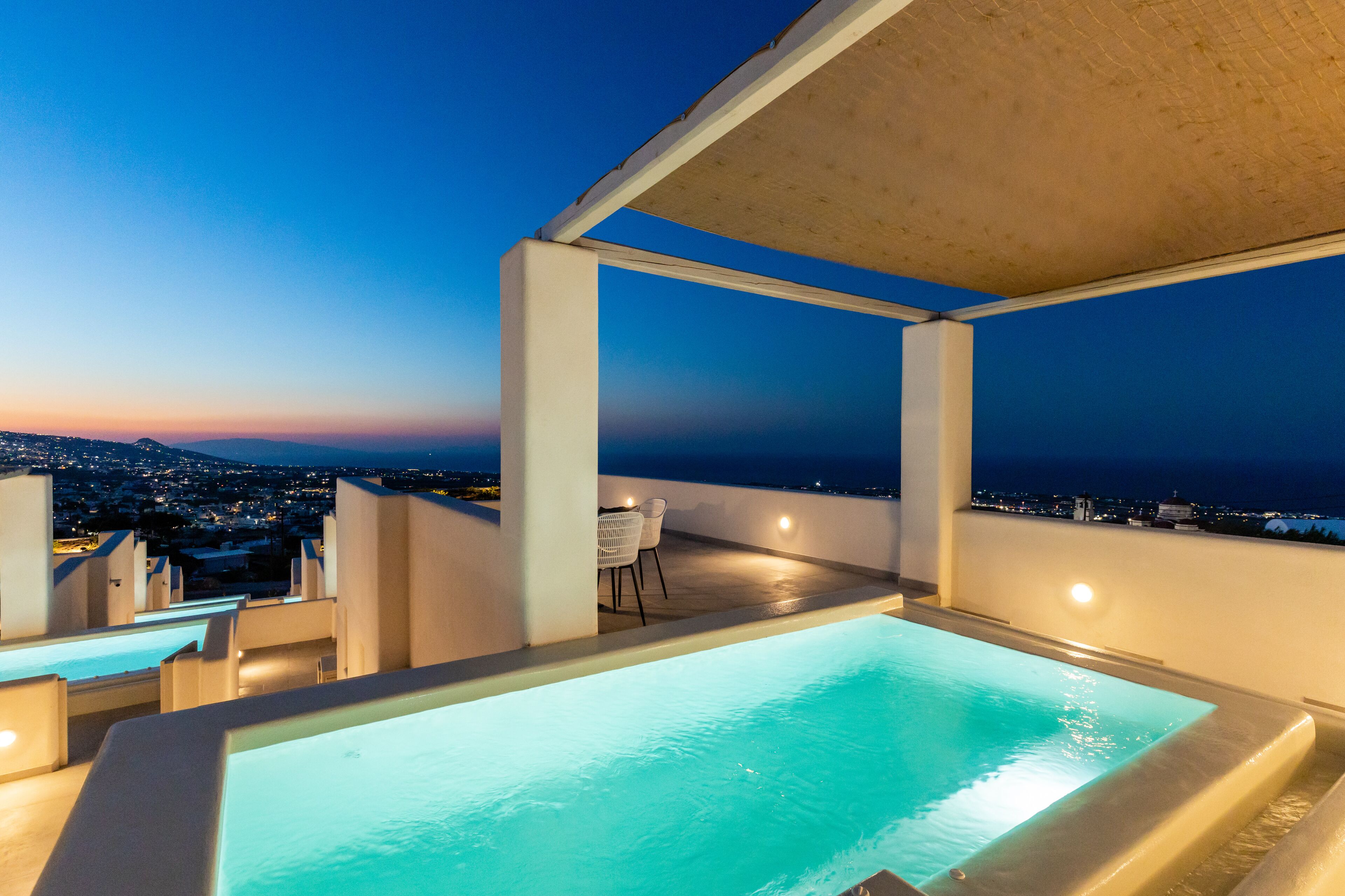 A rooftop pool area with a view of the city at dusk.