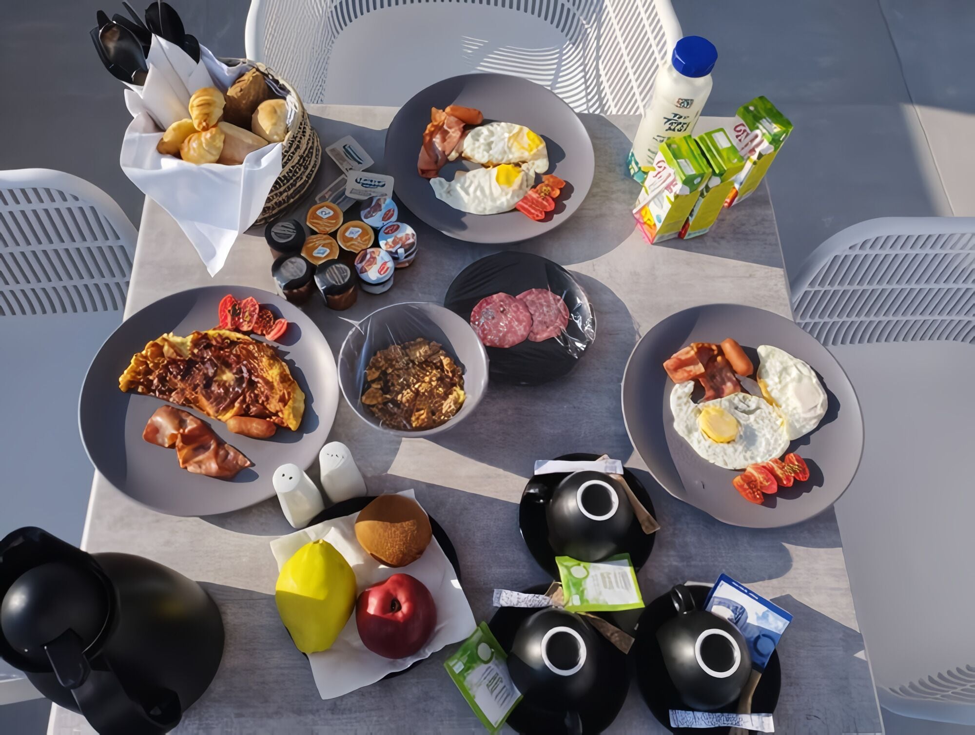 Una mesa con una abundante variedad de alimentos y condimentos para el desayuno.