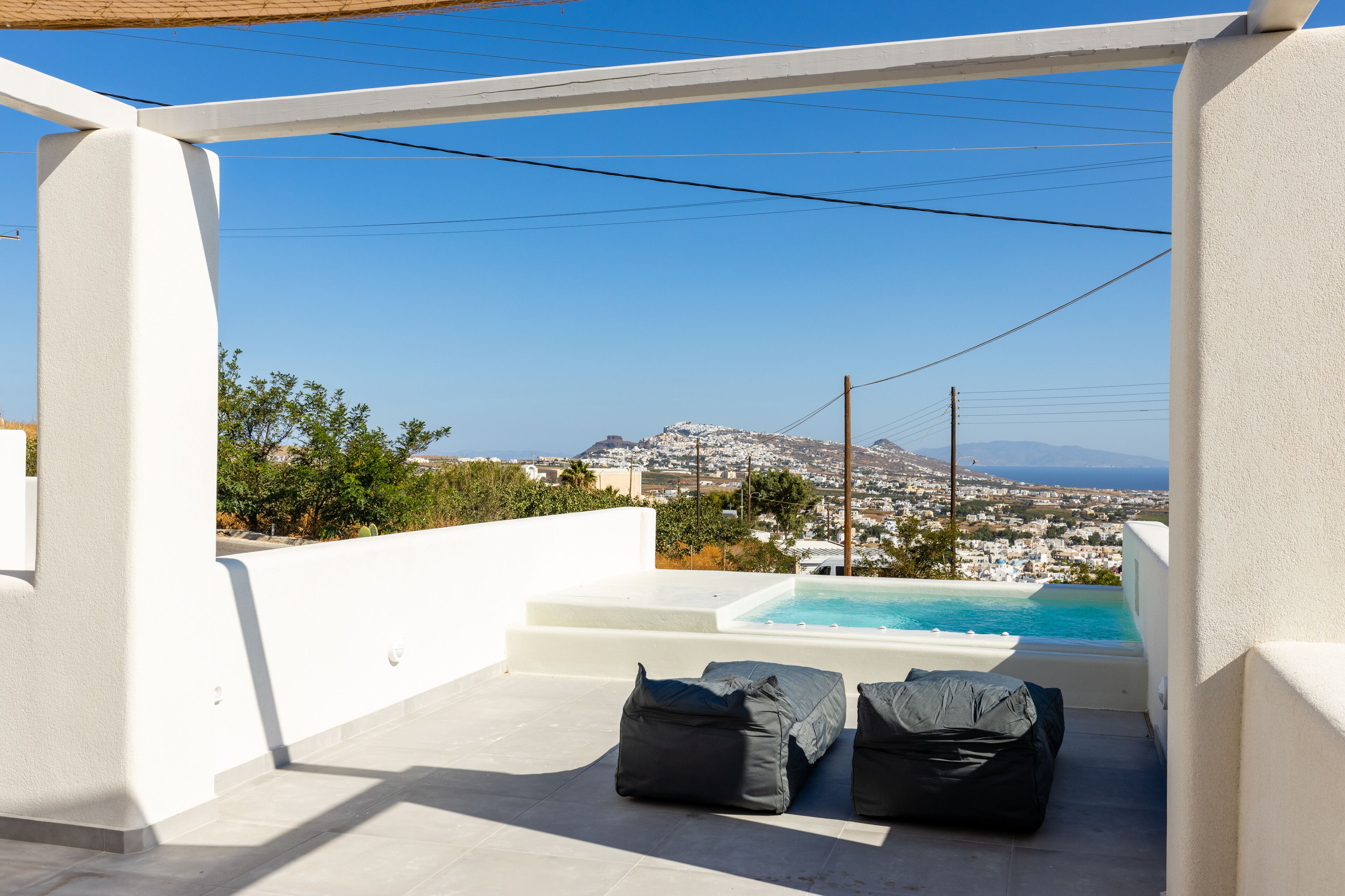 Terraza en la azotea con piscina, paredes blancas y vistas a un pueblo y montañas.