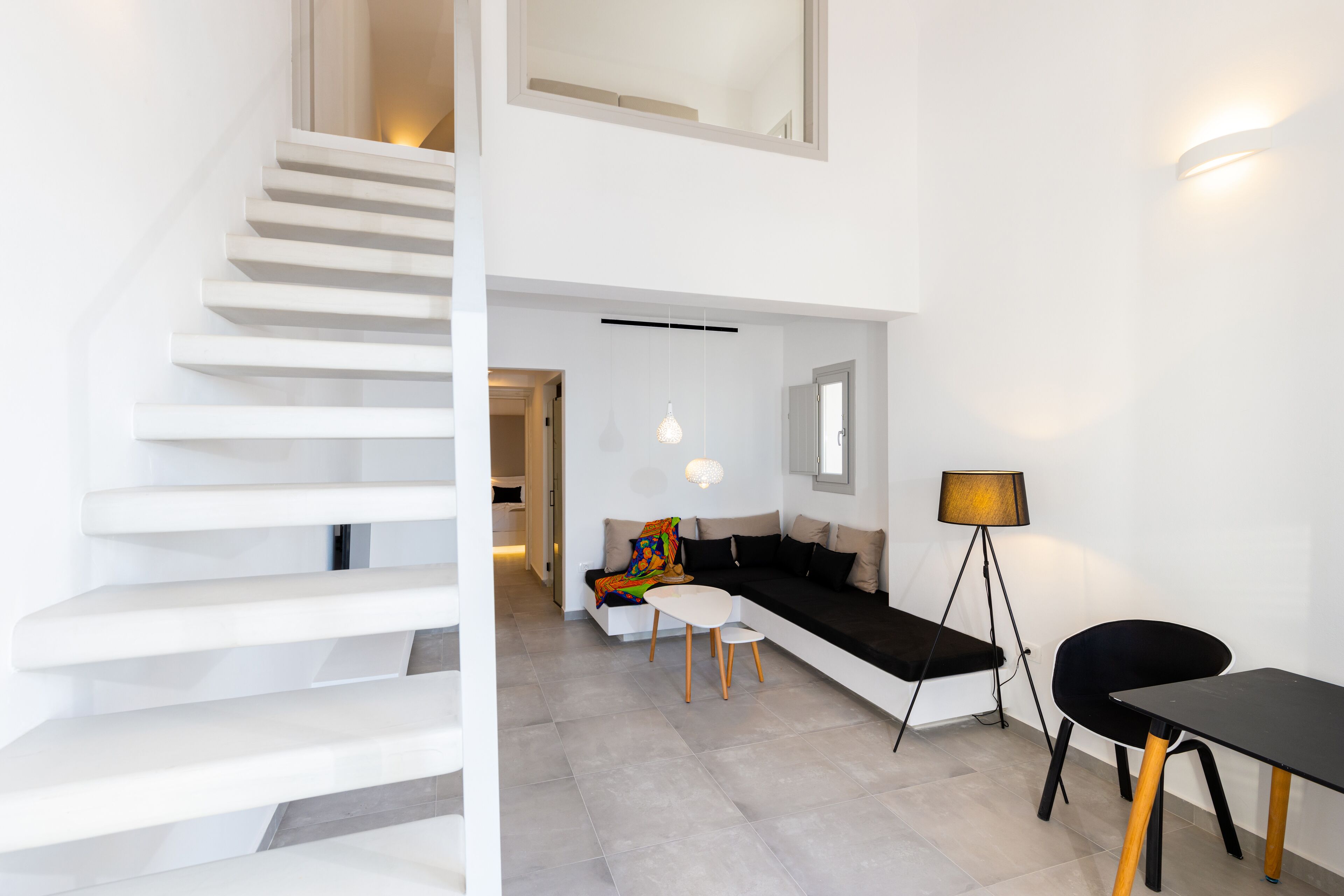 Un interior moderno con una escalera, un sofá, una mesa y una lámpara de pie.