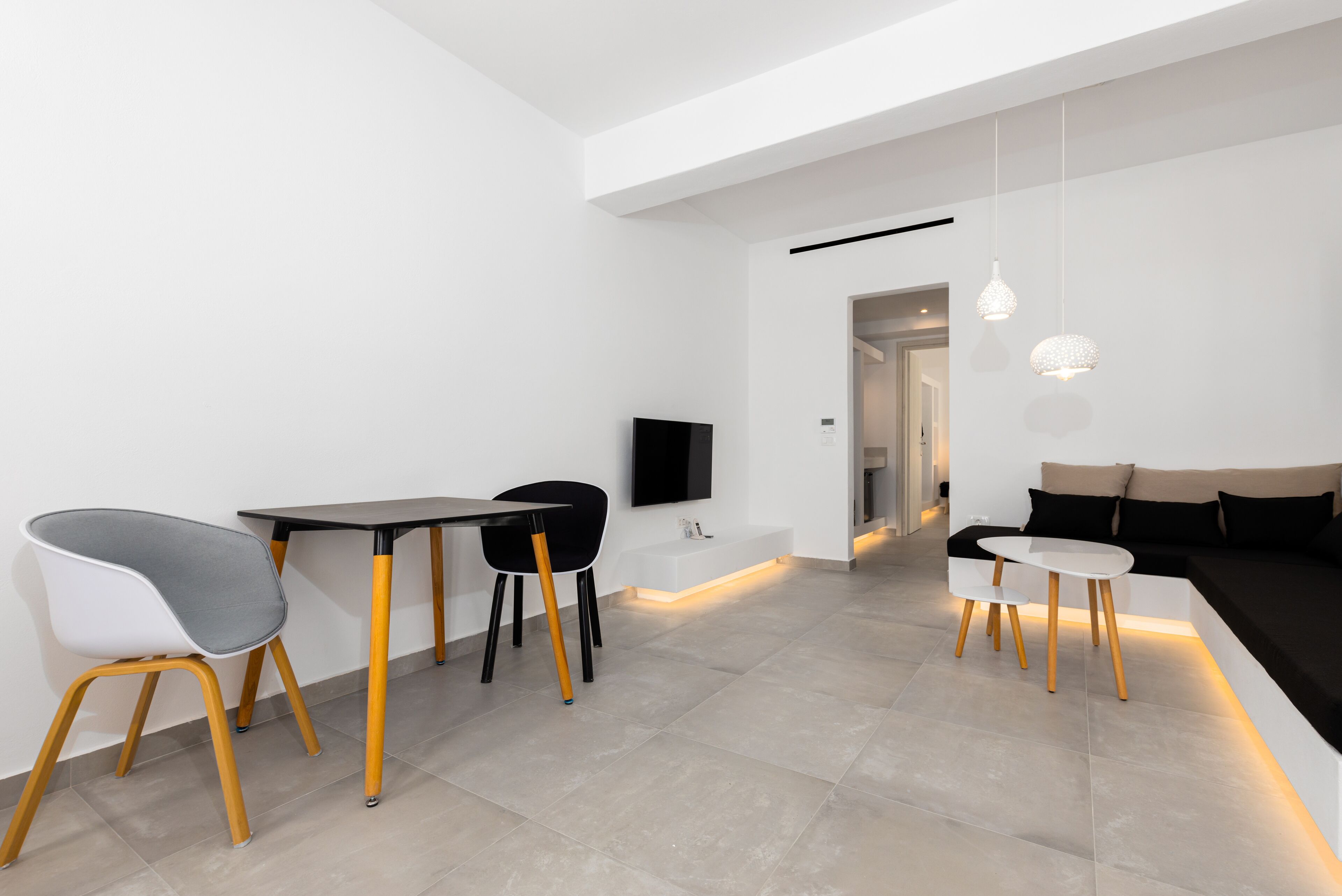 Uma sala de estar moderna com área de jantar, sofá e televisão.