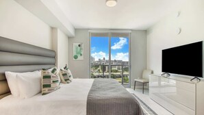 Une chambre d’hôtel moderne dotée d’un grand lit, d’un téléviseur à écran plat, d’une vue sur la ville et d’un design minimaliste.