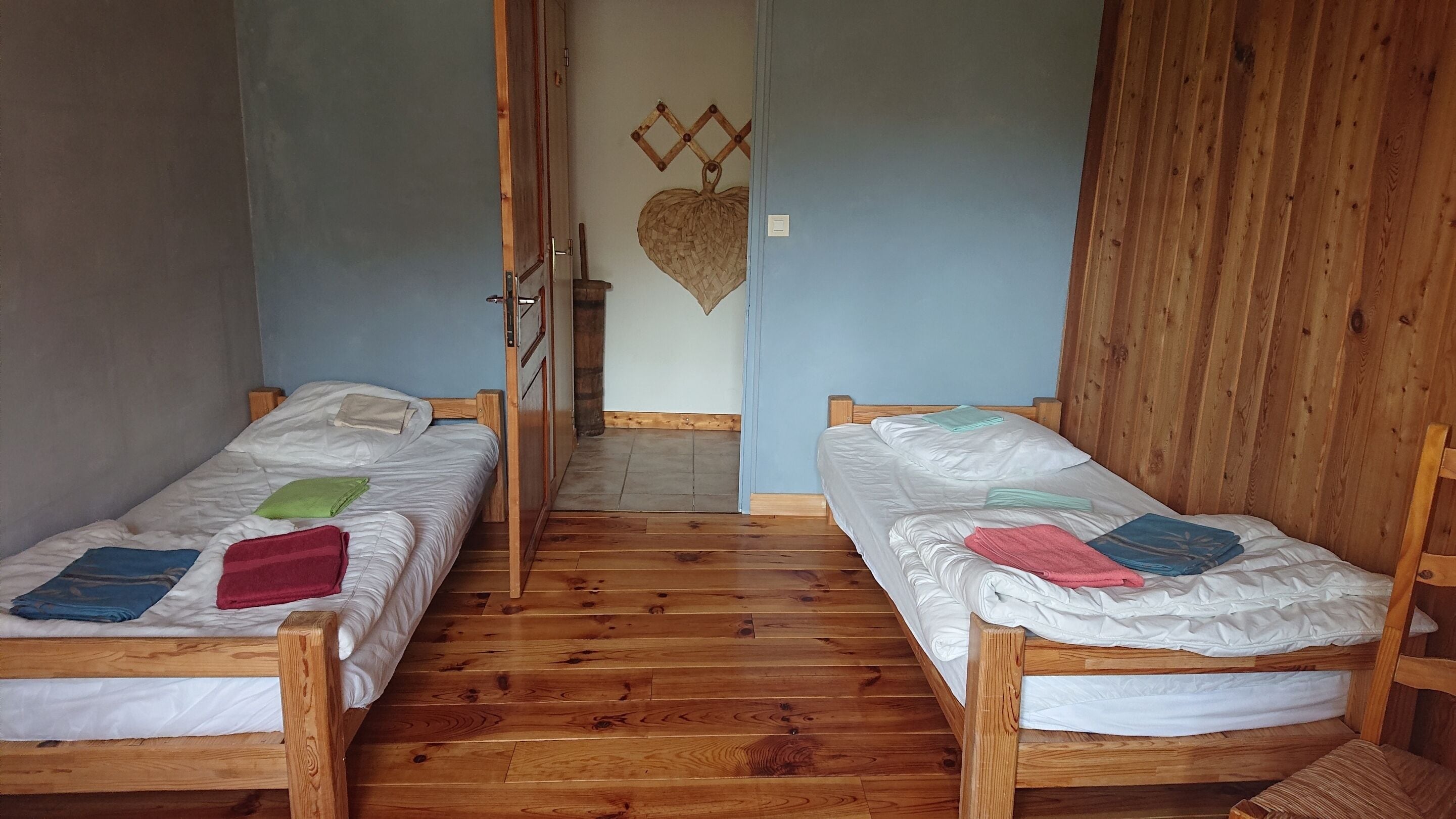 Une pièce avec deux lits superposés en bois, une porte en bois et un décor en forme de cœur fixé au mur.