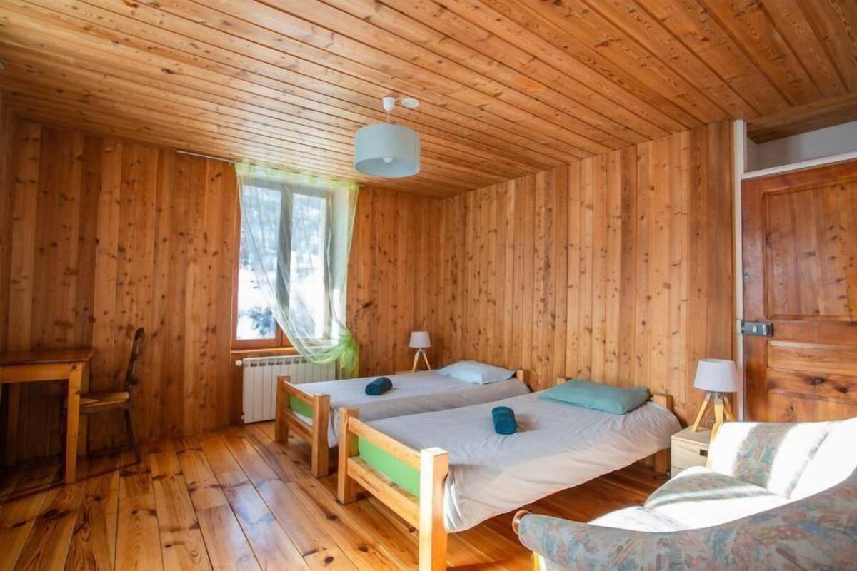 Una cabaña de madera con dos camas individuales, una mesita y una silla.