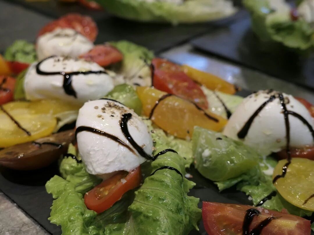 A close-up of a salad with mozzarella balls, tomatoes, and lettuce.