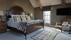A bedroom with a large bed, wooden beams, a television, and a window with a view. - Fillmore Loft at Public House on Elk Ave (Crested Butte)