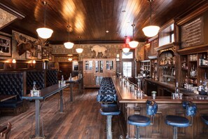A bar with wooden floors, leather booths, and a long counter with stools. - Beacon Loft at Public House on Elk Ave (Crested Butte)