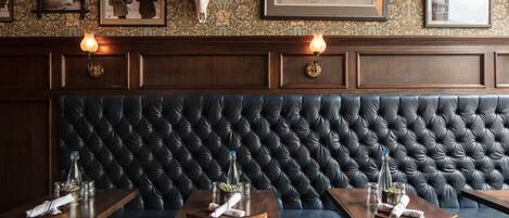 Un restaurant doté d’un banc capitonné de couleur bleu foncé, de photographies encadrées accrochées au mur et d’un grand trophée de cervidé fixé au-dessus de l’espace réservé aux clients.