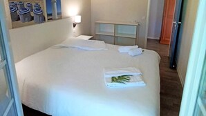 Une chambre d’hôtel avec un grand lit, une table de chevet, une lampe et une armoire.