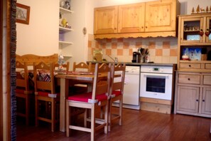 A compact kitchen with wooden cabinets, a dishwasher, and a stove. - L' IDEAL at Ecrin des Neiges. (Vars)