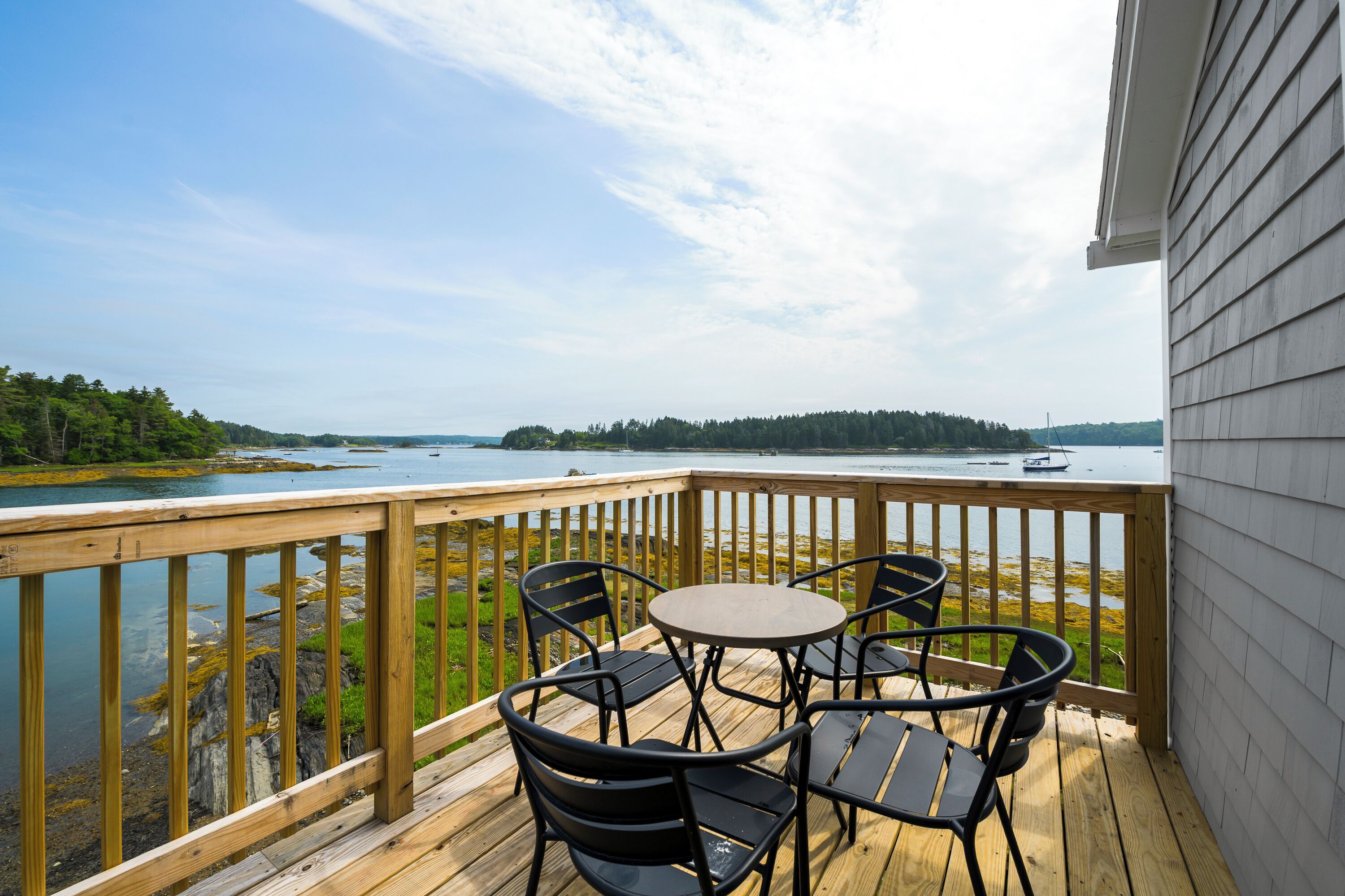 A wooden deck with a table and chairs overlooking a body of water.