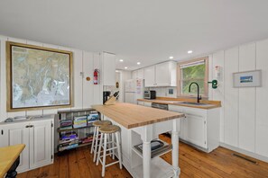 A modern kitchen with white cabinetry, a wooden countertop, and a map on the wall. - Osprey's Nest. Waterfront unit with boat and kayak access. Pet Friendly! (Harpswell)